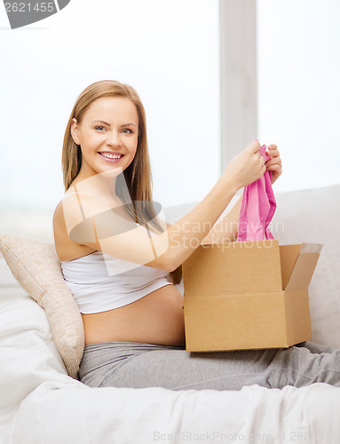 Image of smiling pregnant woman opening parcel box