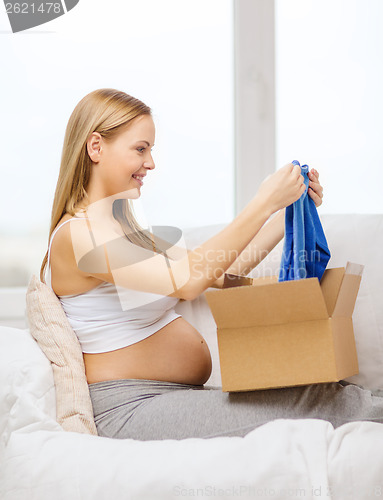 Image of smiling pregnant woman opening parcel box