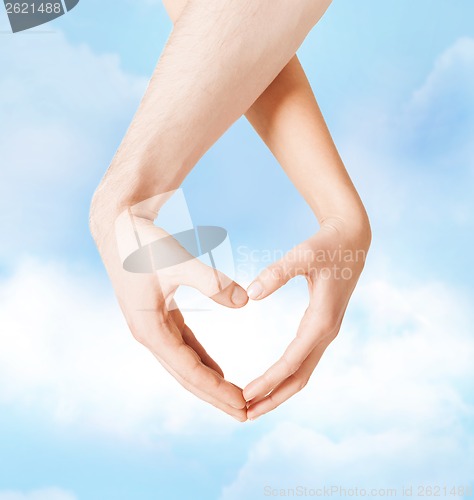 Image of woman and man hands showing heart shape