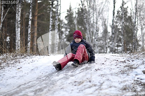 Image of the teenage boy rides from a hill in the snow-covered wood.