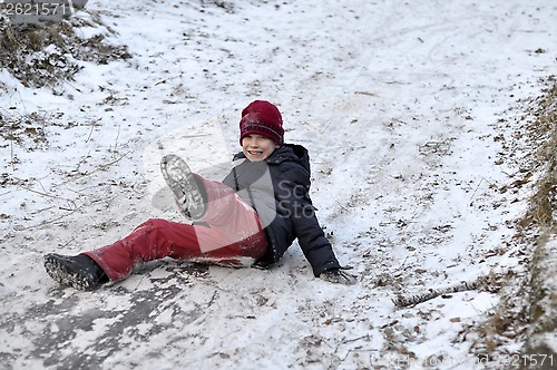 Image of the teenage boy rides from a hill in the snow-covered wood.