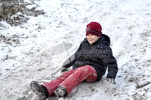 Image of the teenage boy rides from a hill in the snow-covered wood.