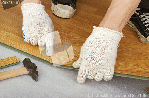 Image of Hands of a master, lay laminate flooring