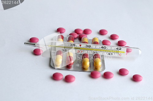 Image of The increased temperature on a thermometer, pills and tablets.