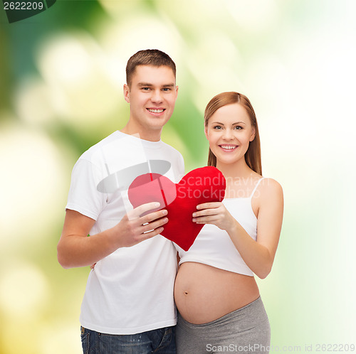 Image of happy young family expecting child with big heart