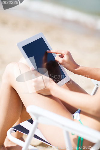 Image of girl looking at tablet pc on the beach