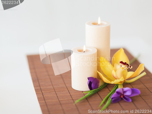 Image of candles, orchid and iris flowers on bamboo mat