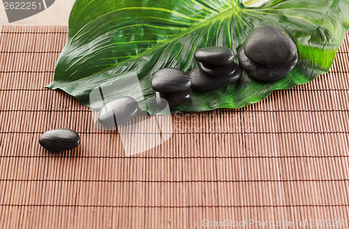 Image of massage stones with flowers on mat