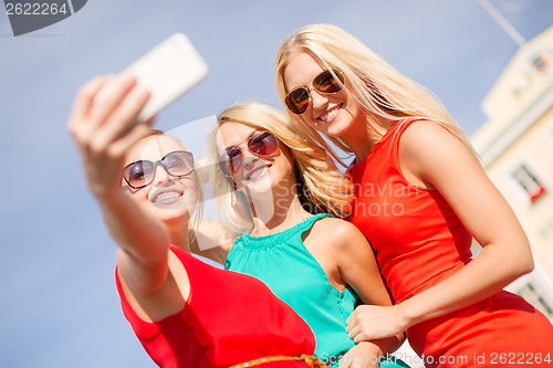 Image of smiling girls taking photo with smartphone camera