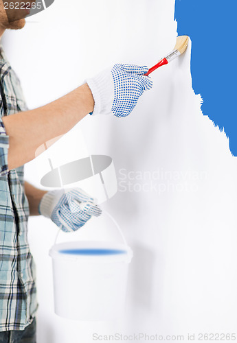 Image of man with paintbrush and pot painting wall