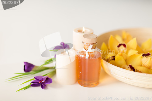 Image of orchid flowers in bowl, oil, candles and irises