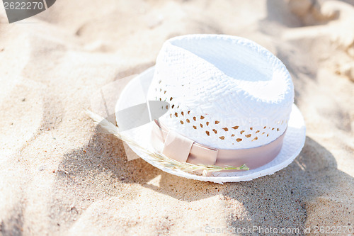 Image of white straw hat lying in the sand on the beach