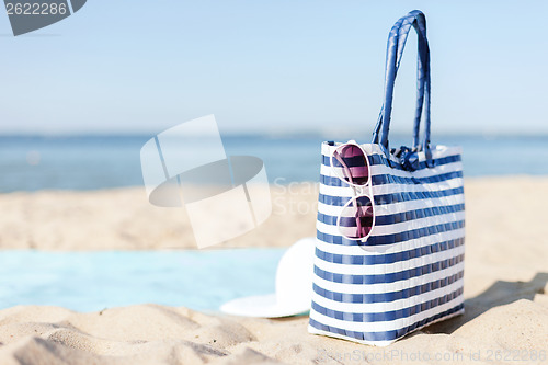 Image of straw hat, sunglasses and bag lying in the sand