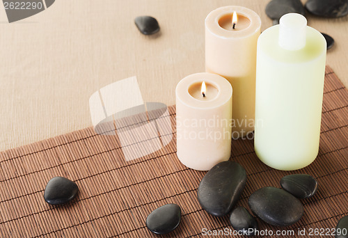 Image of shampoo bottle, massage stones and candles