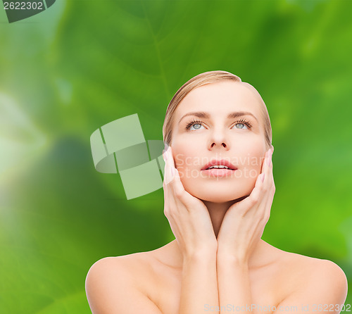 Image of beautiful woman touching her face and looking up