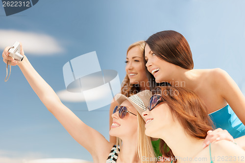 Image of smiling girls taking photo in cafe on the beach