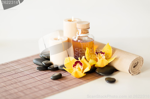 Image of essential oil, massage stones and orchid flower