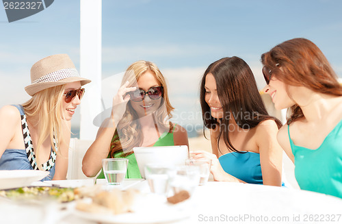 Image of smiling girls looking at tablet pc in cafe