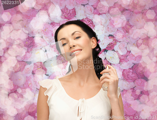 Image of beautiful woman spraying pefrume on her neck