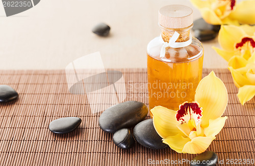 Image of essential oil, massage stones and orchid flowers