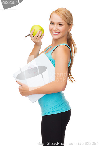 Image of sporty woman with scale and green apple