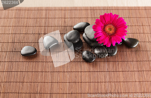 Image of massage stones with flower on mat