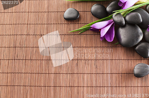 Image of massage stones with flowers on mat