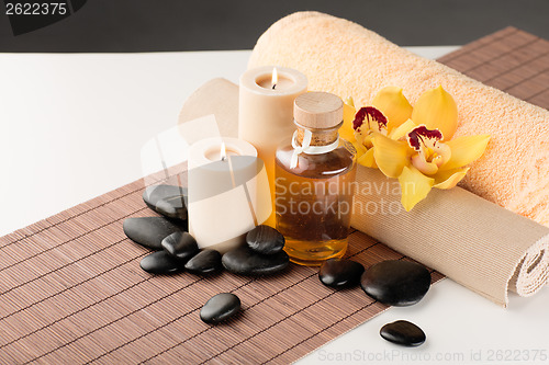 Image of essential oil, massage stones and orchid flower