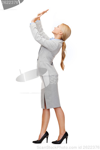 Image of businesswoman pushing up something imaginary