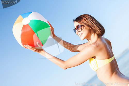 Image of girl in bikini playing ball on the beach