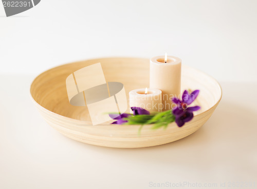 Image of candles and iris flowers in wooden bowel