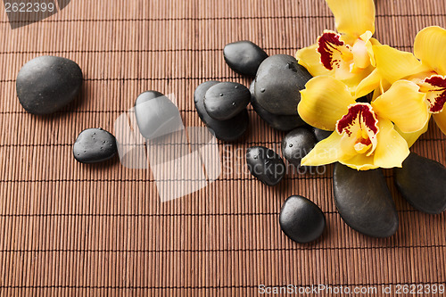 Image of massage stones with flowers on mat