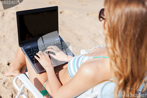 Image of girl looking at laptop on the beach