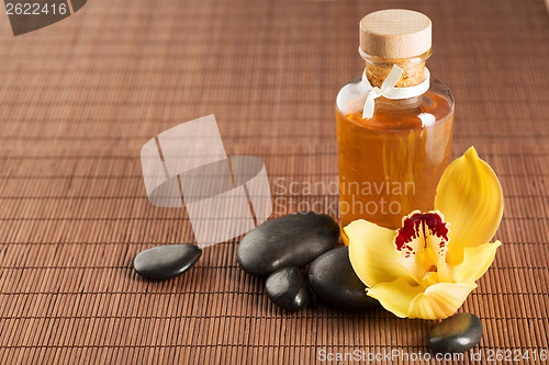 Image of essential oil, massage stones and orchid flower