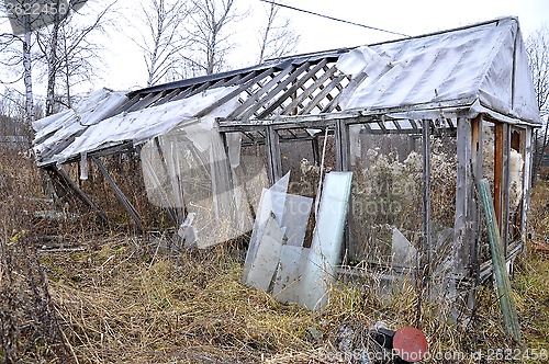 Image of the old broken wooden greenhouse in a kitchen garden.