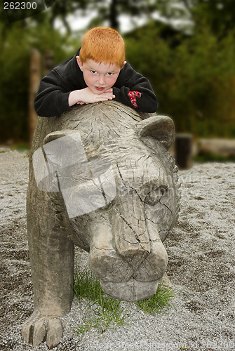 Image of kid lying on a wooden lion