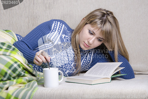 Image of Girl reading book under a blanket on couch