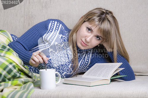 Image of Girl reading book under a blanket on couch