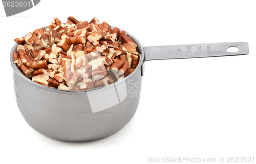 Image of Chopped pecan nuts in a metal cup measure