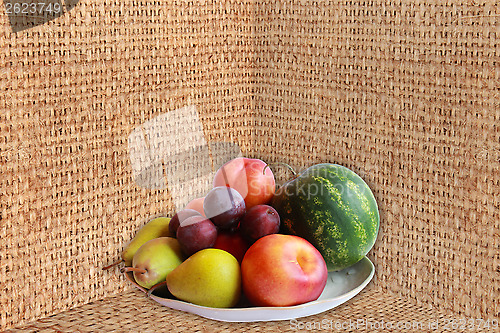 Image of watermelon, pears and plums on the sacking