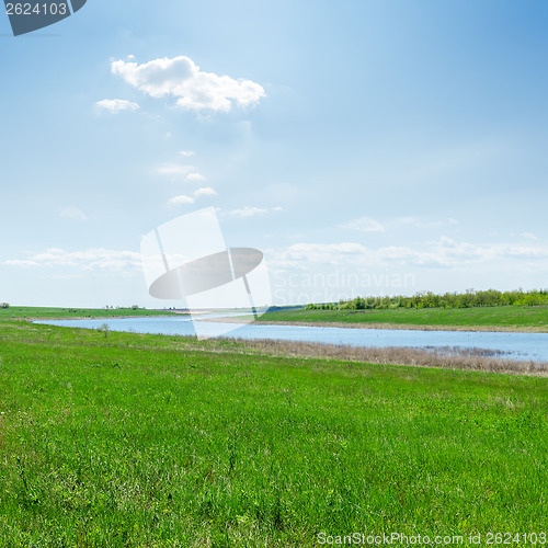 Image of river in green grass and clouds over it