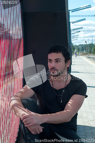 Image of Young andsome man sitting on platform