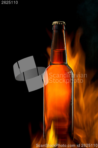 Image of Beer bottle in fire on black