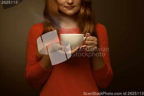 Image of woman holding hot cup and smiles