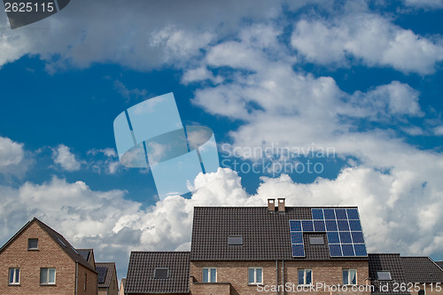 Image of New houses with solar panels on roof under blue sky and clouds