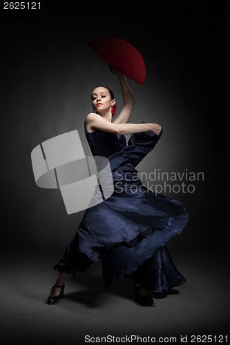 Image of young woman dancing flamenco on black