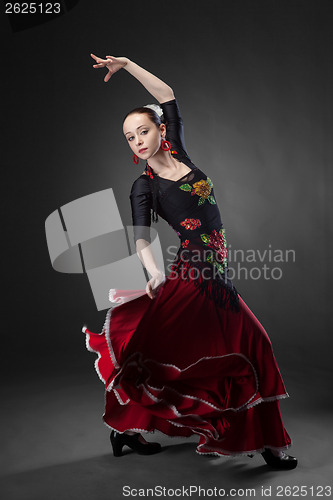 Image of young woman dancing flamenco on black