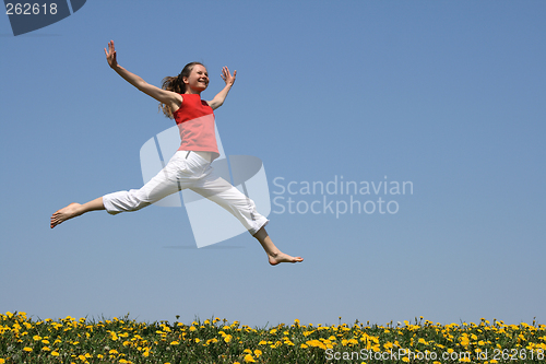 Image of Girl flying in a jump over flowering field