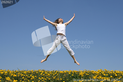 Image of Smiling girl jumping in flowering meadow