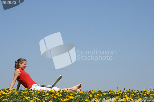 Image of Young woman relaxing with laptop outdoors